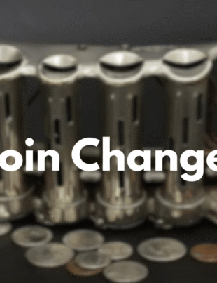 Vintage metal four-tube coin changer with coins.