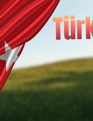 Turkish flag draped over a blurred green field landscape with the text "Türk Idla."