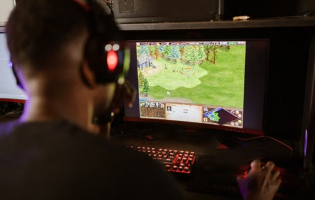 A gamer playing a strategy game on a PC setup with a headset.