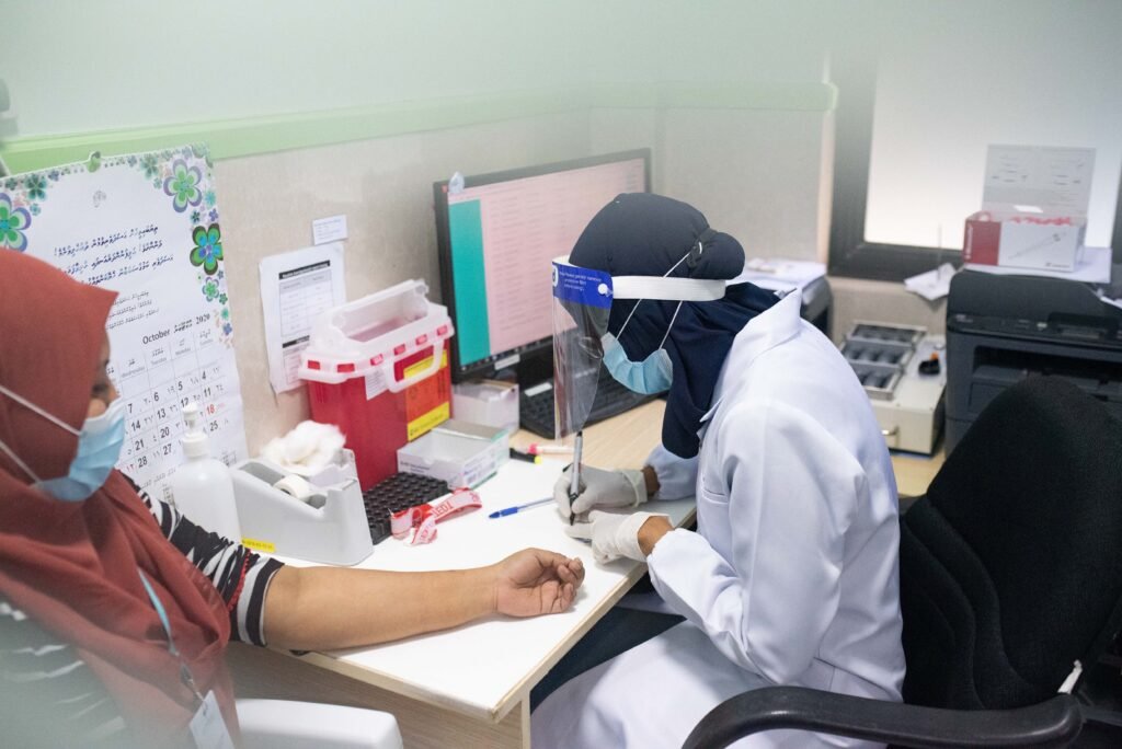 Healthcare provider wearing protective gear documenting patient details, demonstrating Medicines Ethics and Practice during a medical procedure.