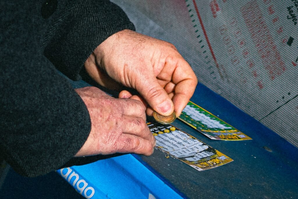 Premier Lotteries scratch card being played with a coin