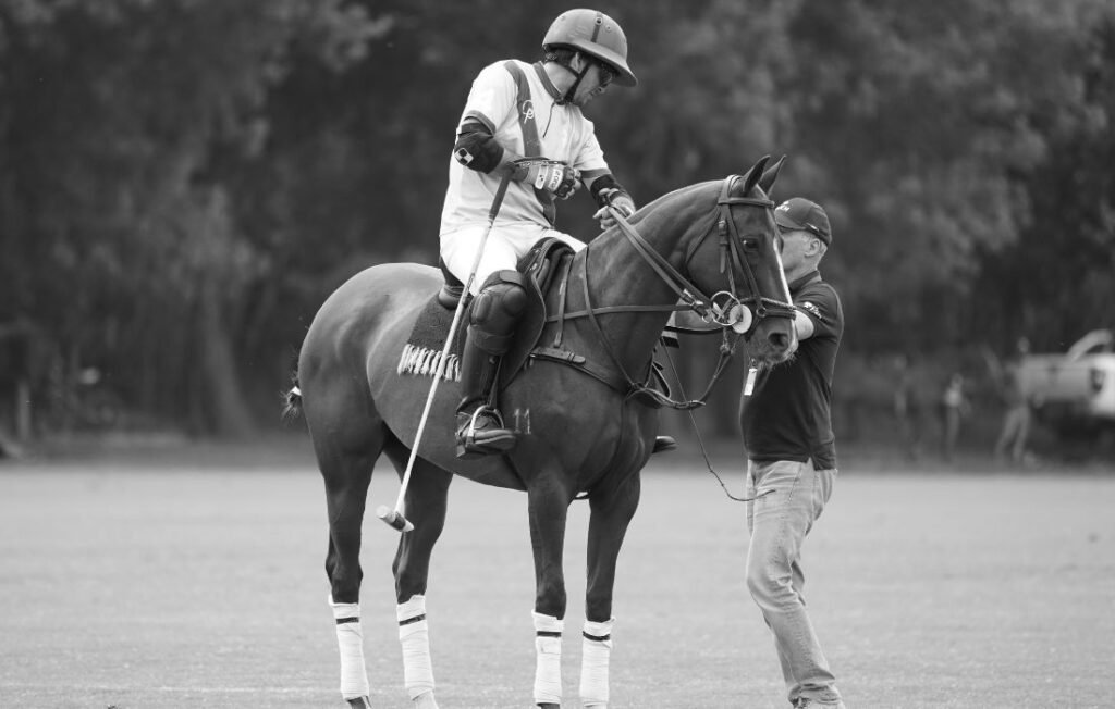 Polo player on horseback with coach during an outdoor match