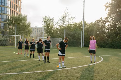 Football coach leading players through drills while wearing the Forest Command Coach Polo on the training pitch.